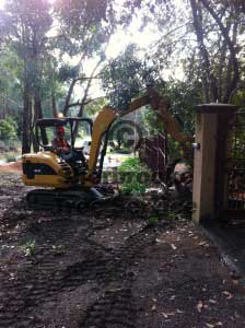 the excavator lifts firewood back over the fence